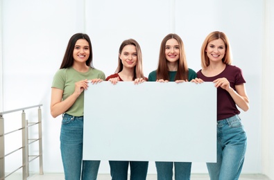 Photo of Portrait of happy ladies with empty poster indoors, space for text. Women power concept