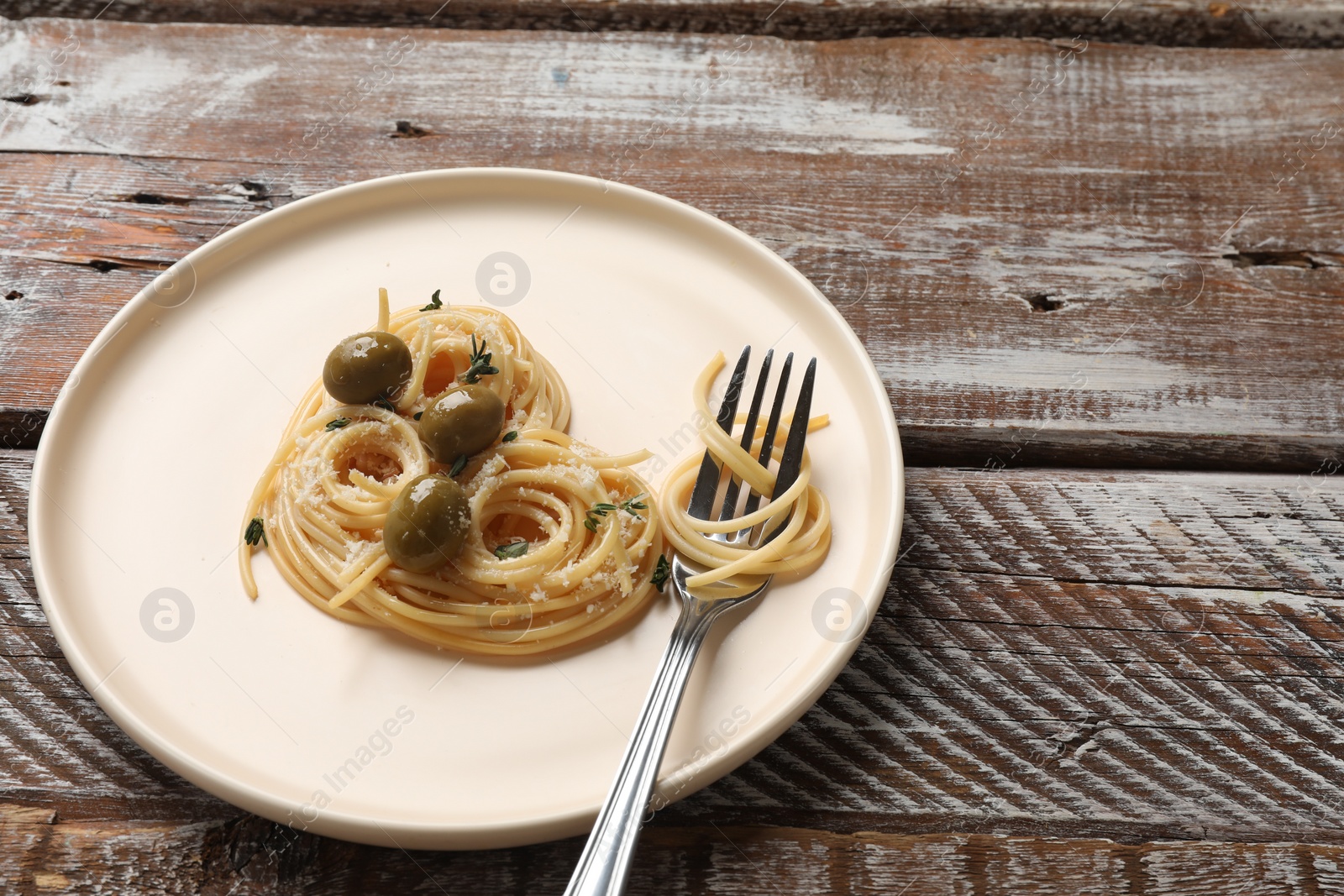 Photo of Heart made of tasty spaghetti, fork, olives and cheese on wooden table. Space for text