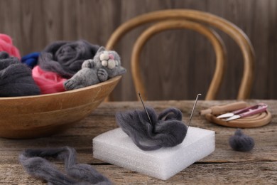 Photo of Felting tools, wool and toy cat on wooden table