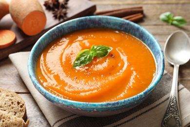 Bowl of tasty sweet potato soup served on table, closeup