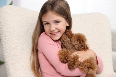 Photo of Little child with cute puppy in armchair indoors. Lovely pet