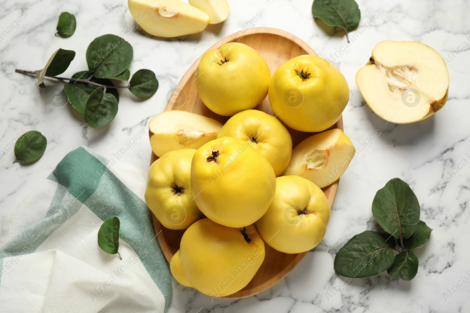 Photo of Fresh ripe organic quinces with leaves on white marble table, flat lay