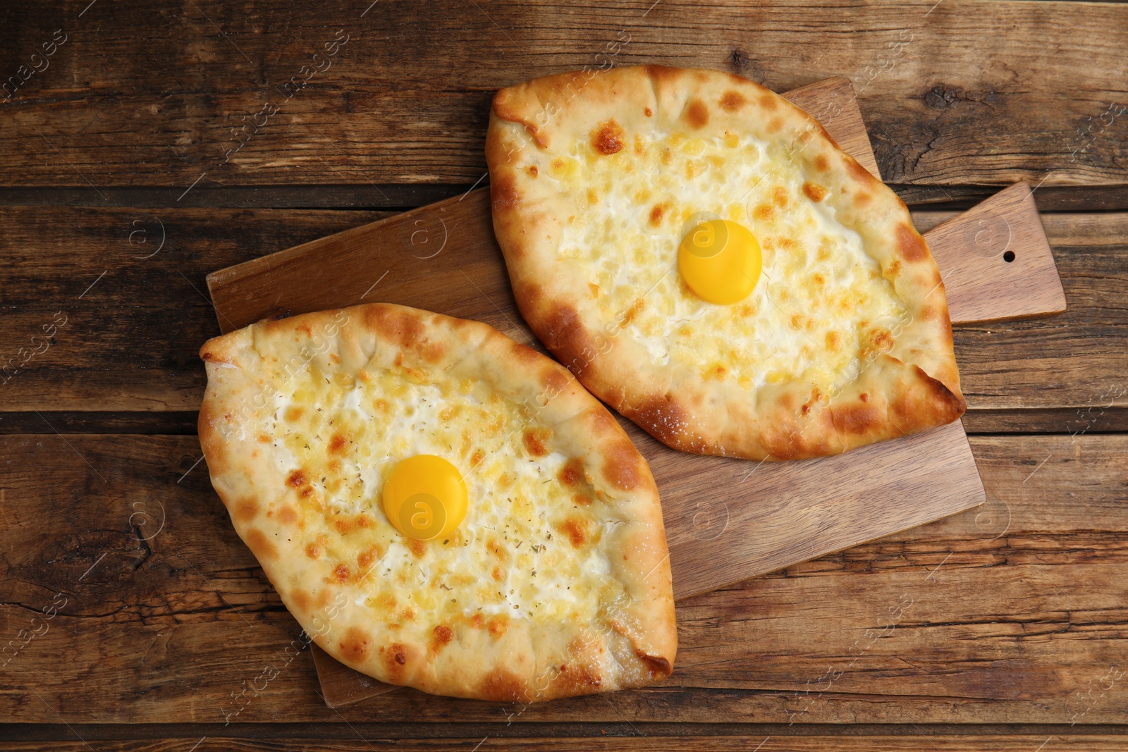 Photo of Fresh homemade khachapuri with cheese and egg on wooden table, top view