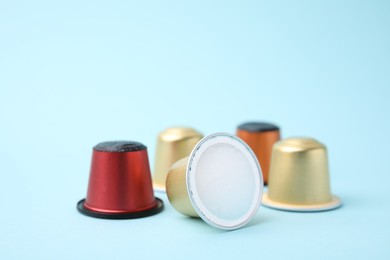 Many coffee capsules on light blue background, closeup