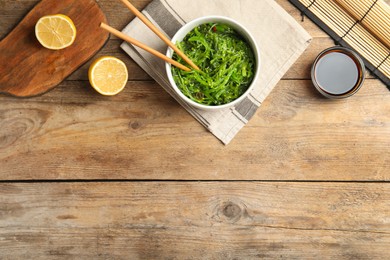 Photo of Japanese seaweed salad served on wooden table, flat lay. Space for text