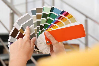 Photo of Female interior designer with color palette samples indoors, closeup