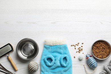 Photo of Flat lay composition with cat clothes, food and accessories on white wooden table. Space for text