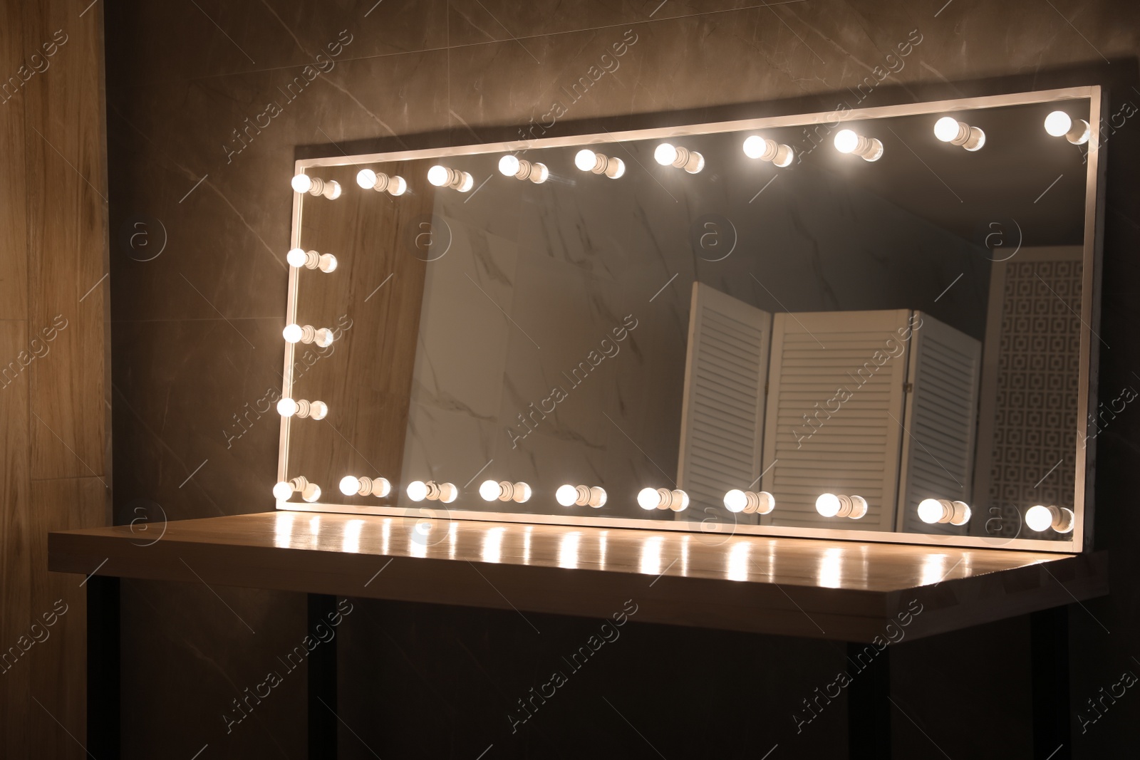 Photo of Modern mirror with light bulbs on wooden table in room