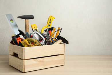 Photo of Crate with different carpenter's tools on wooden table. Space for text