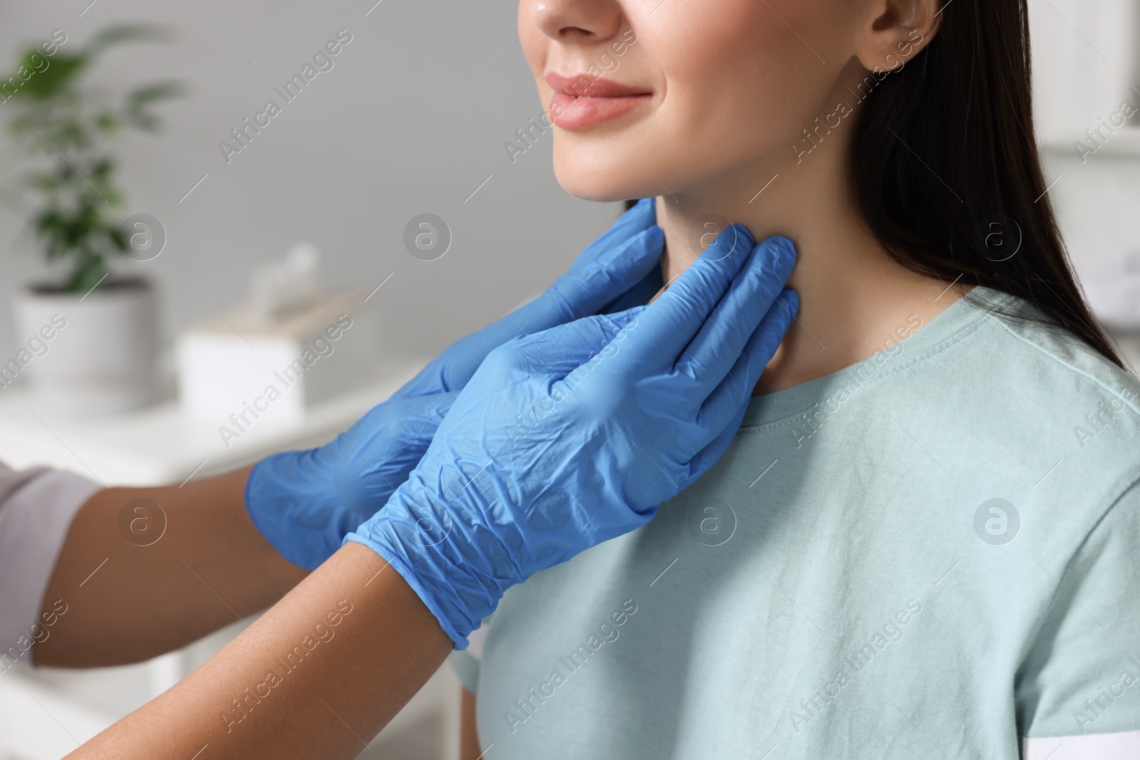 Photo of Endocrinologist examining thyroid gland of patient indoors, closeup