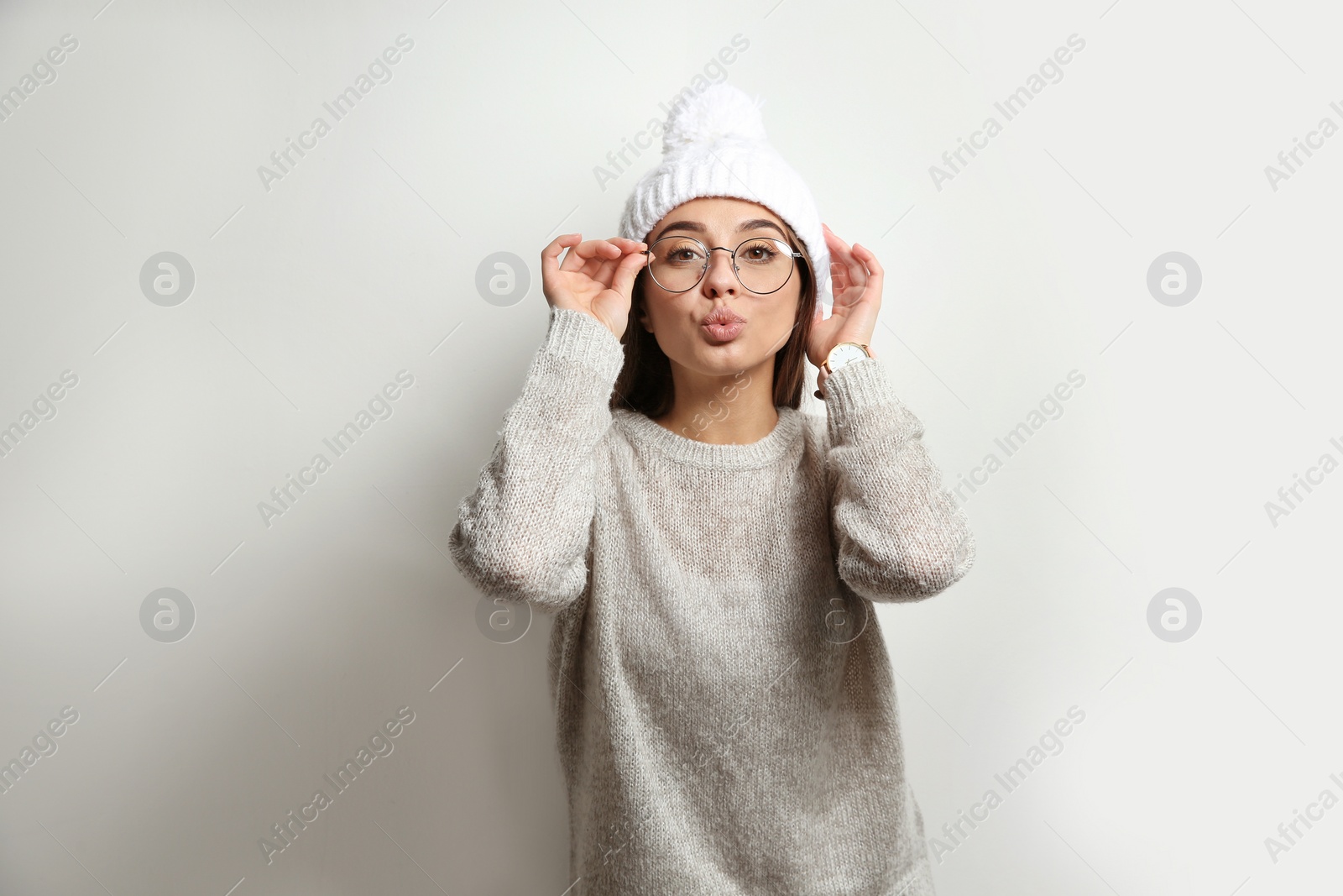 Photo of Beautiful young woman in warm sweater with hat on white background