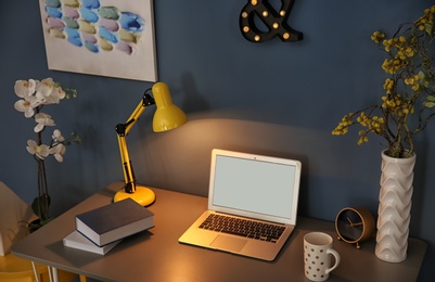 Photo of Comfortable workplace with laptop on desk in home office