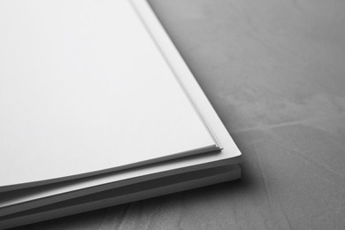 Photo of Blank paper sheets on light grey stone background, closeup. Mock up for design