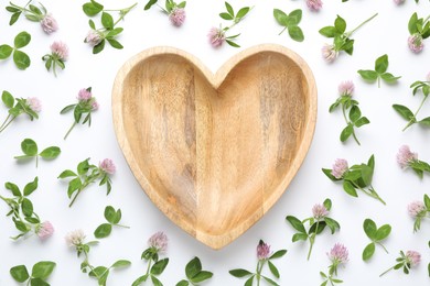 Beautiful clover flowers with heart shaped plate on white background, flat lay