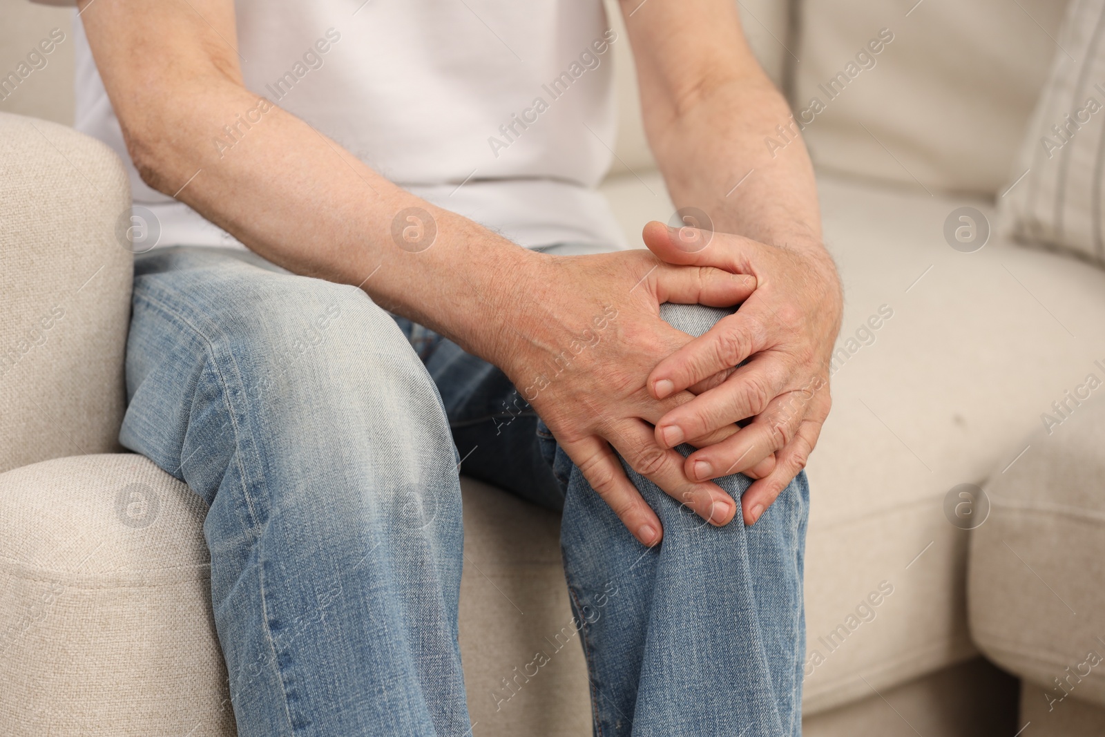 Photo of Senior man suffering from knee pain on sofa, closeup. Rheumatism symptom