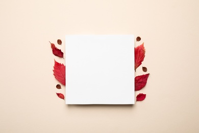 Flat lay composition with autumn leaves and blank card on light background, space for text