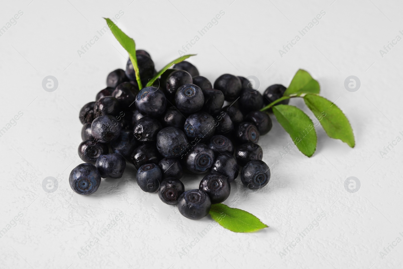 Photo of Pile of ripe bilberries and leaves on white background