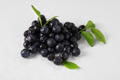 Pile of ripe bilberries and leaves on white background