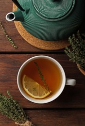 Aromatic herbal tea with thyme and lemon on wooden table, flat lay
