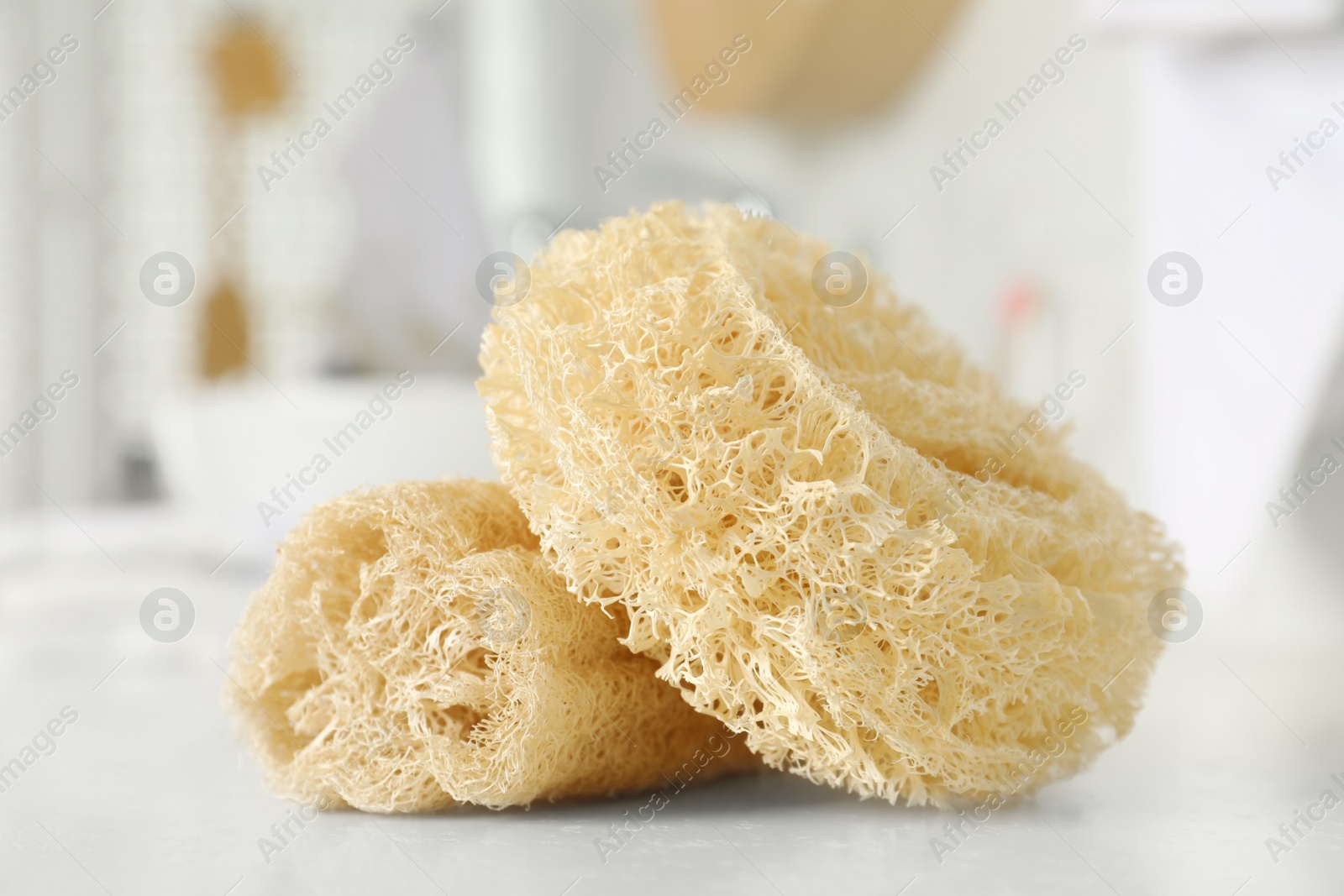 Photo of Natural loofah sponges on table in bathroom, closeup