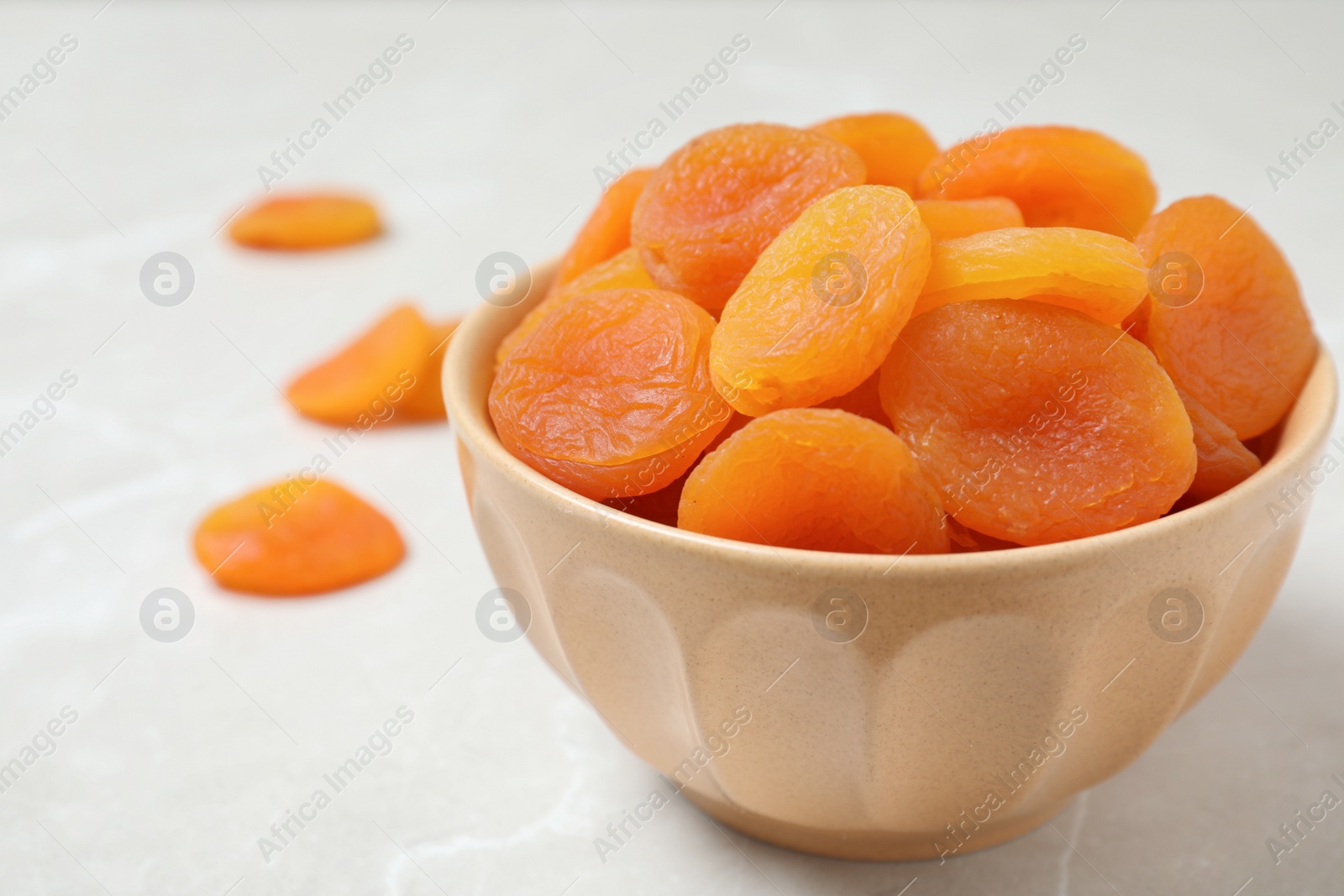 Photo of Bowl with apricots on grey background. Dried fruit as healthy food