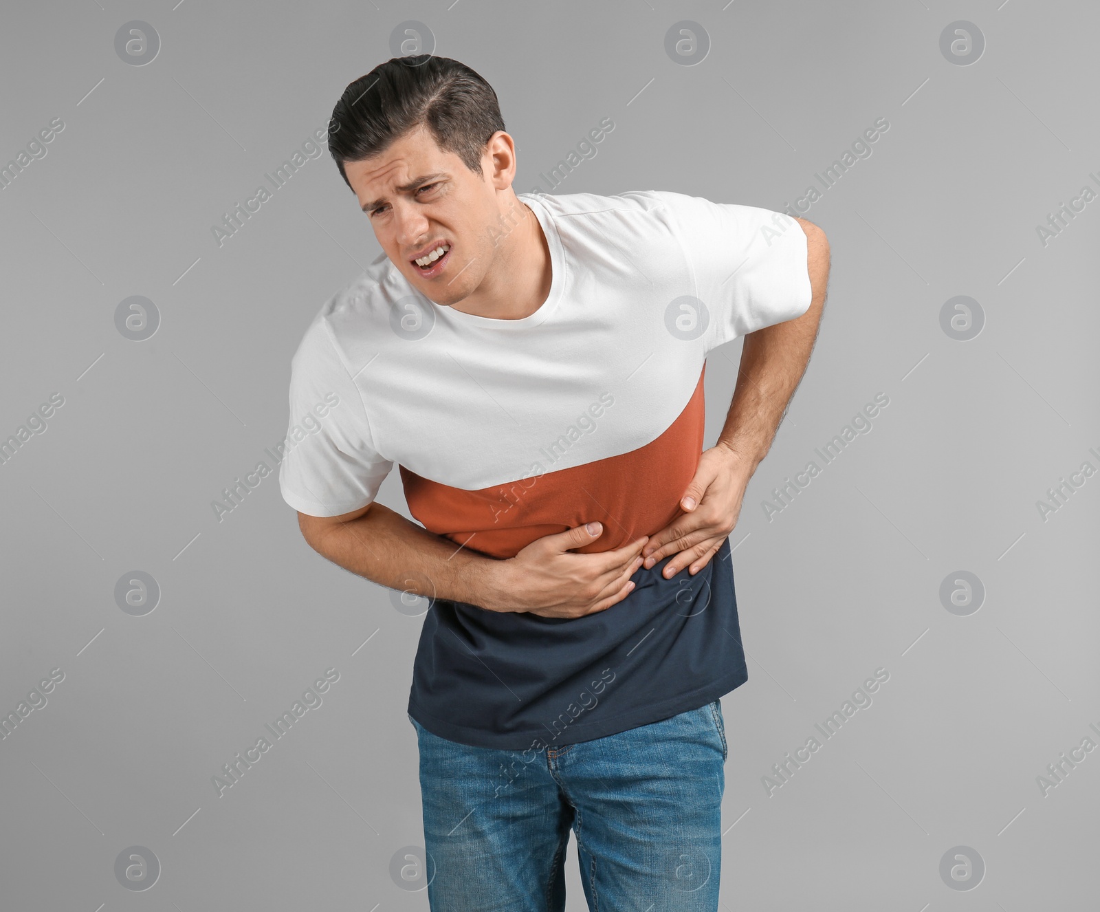 Photo of Young man suffering from abdominal pain on grey background