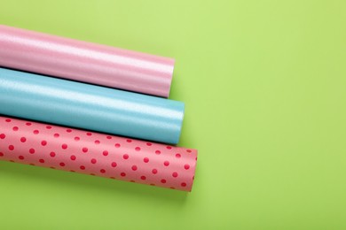 Photo of Rolls of colorful wrapping papers on green background, flat lay. Space for text