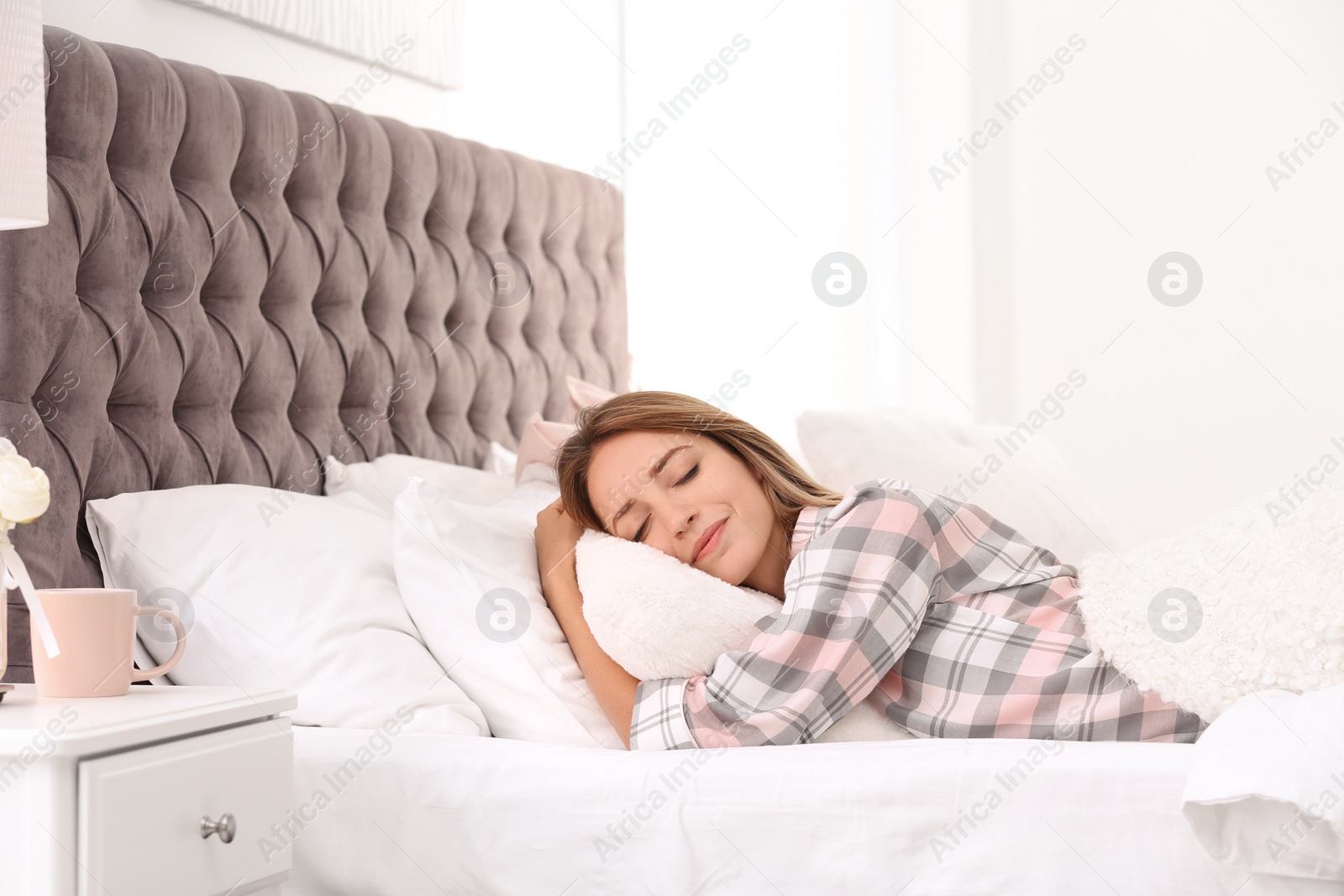 Photo of Young woman sleeping on soft pillows in bed at home