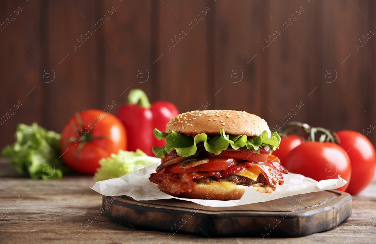 Photo of Tasty burger with bacon on wooden table. Space for text