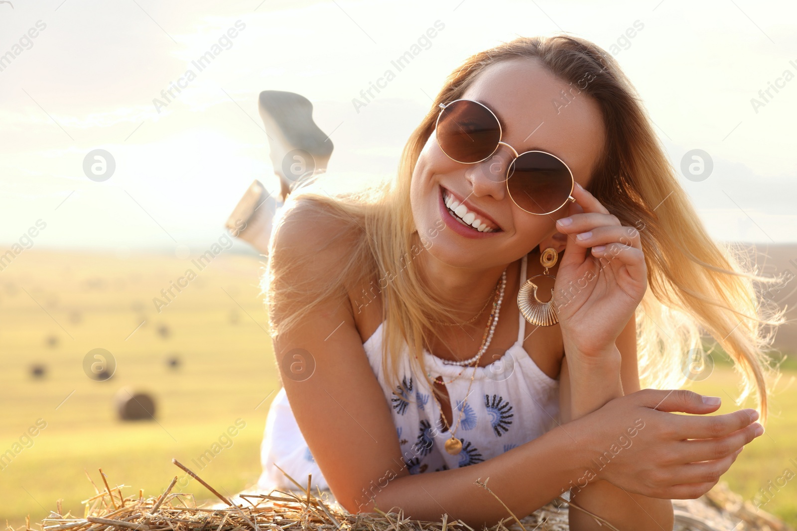 Photo of Beautiful hippie woman on hay bale in field, space for text