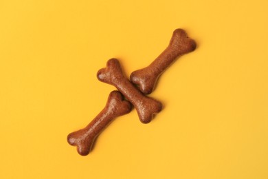 Photo of Bone shaped dog cookies on orange background, flat lay