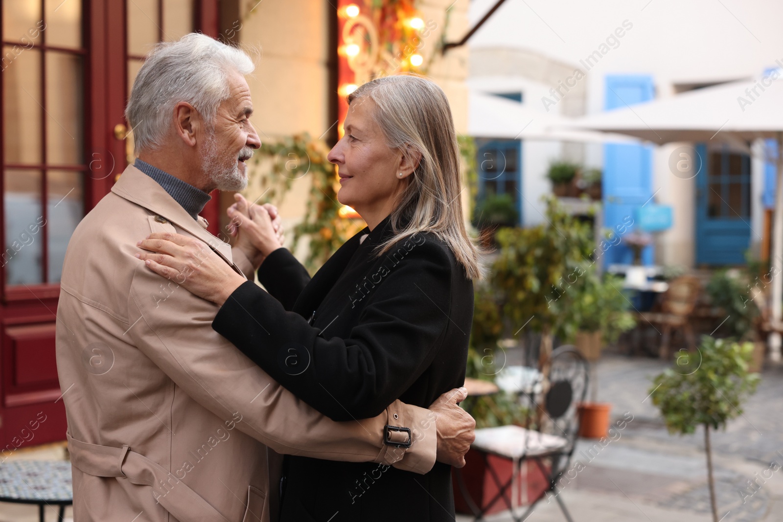 Photo of Affectionate senior couple dancing together on city street, space for text