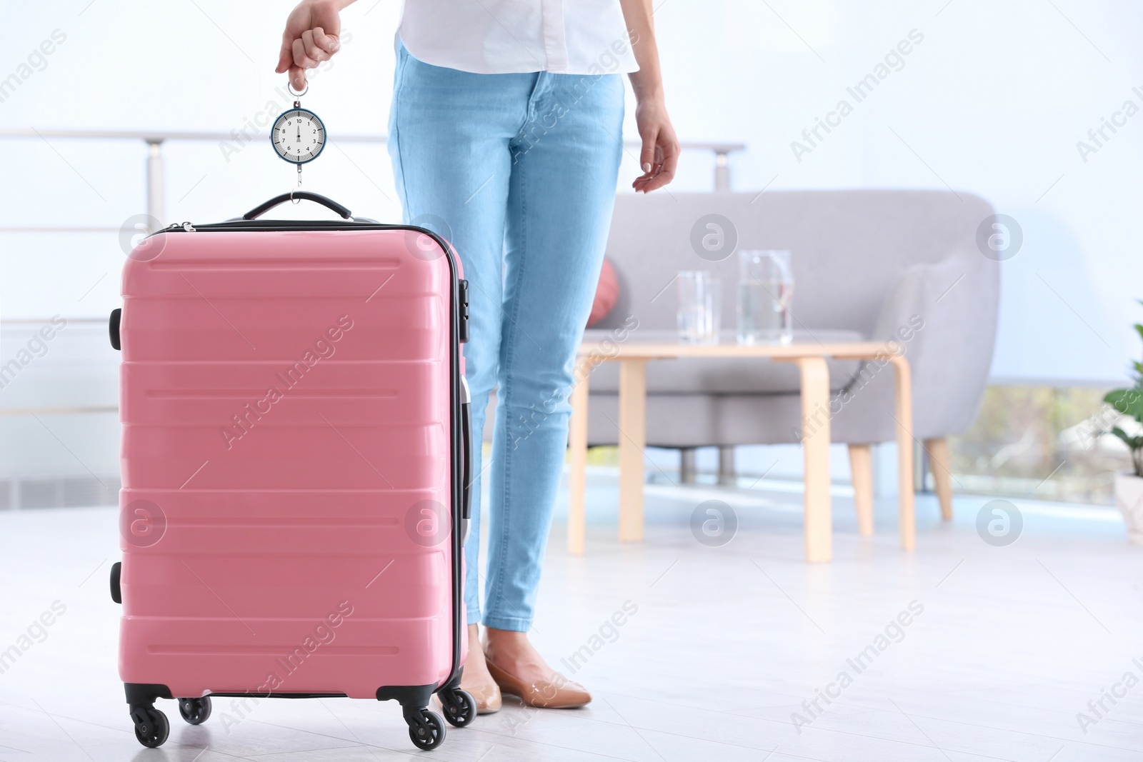 Photo of Woman weighing suitcase indoors. Space for text