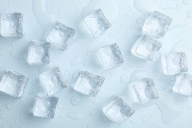 Crystal clear ice cubes on light blue background, flat lay