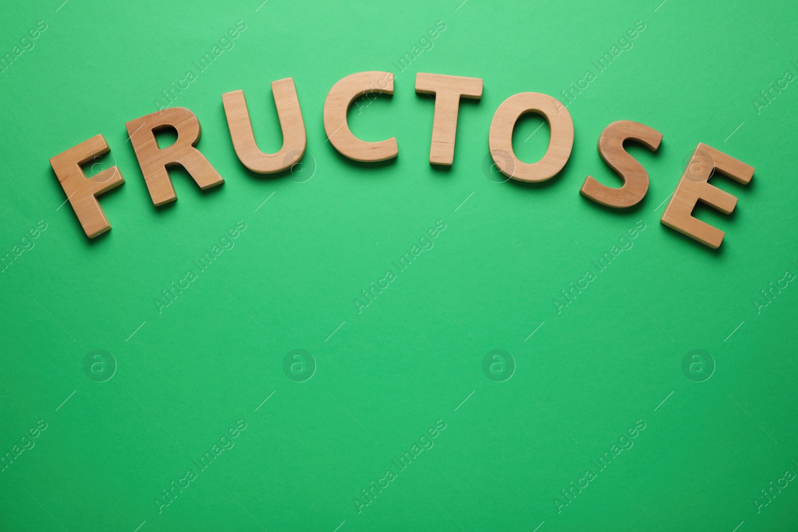 Photo of Word Fructose made of wooden letters on green background, flat lay. Space for text