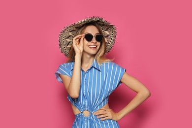 Photo of Beautiful young woman wearing straw hat and sunglasses on crimson background. Stylish headdress