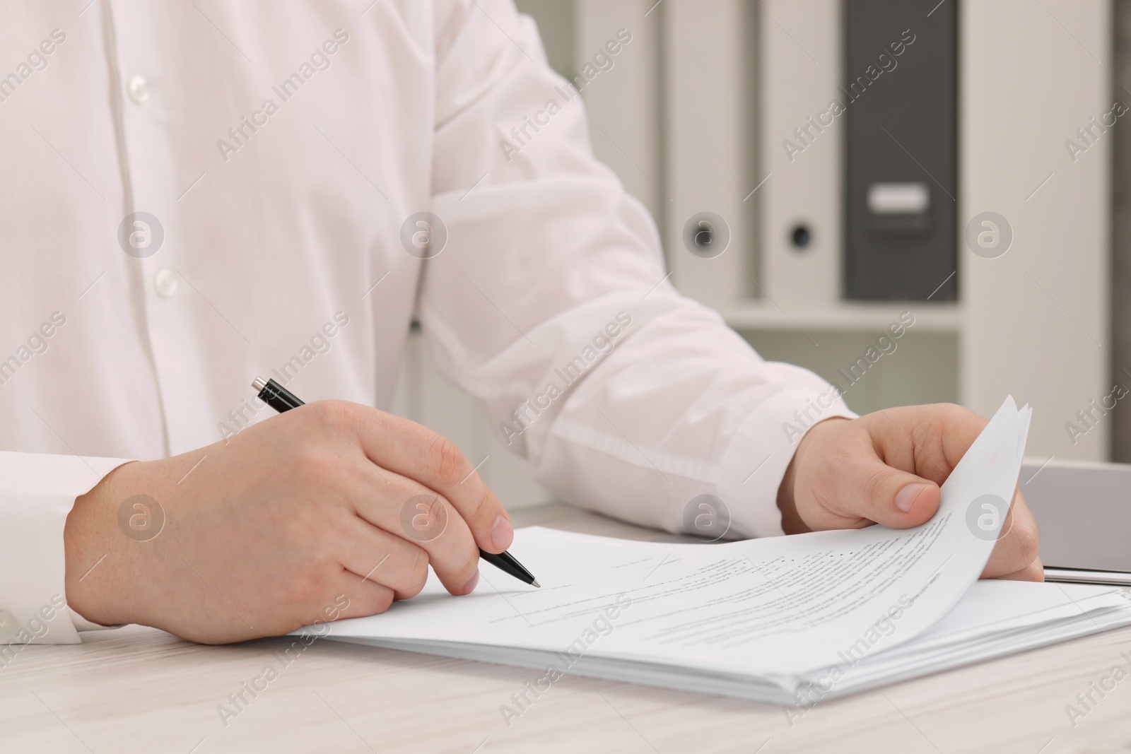 Photo of Man signing document at wooden table, closeup