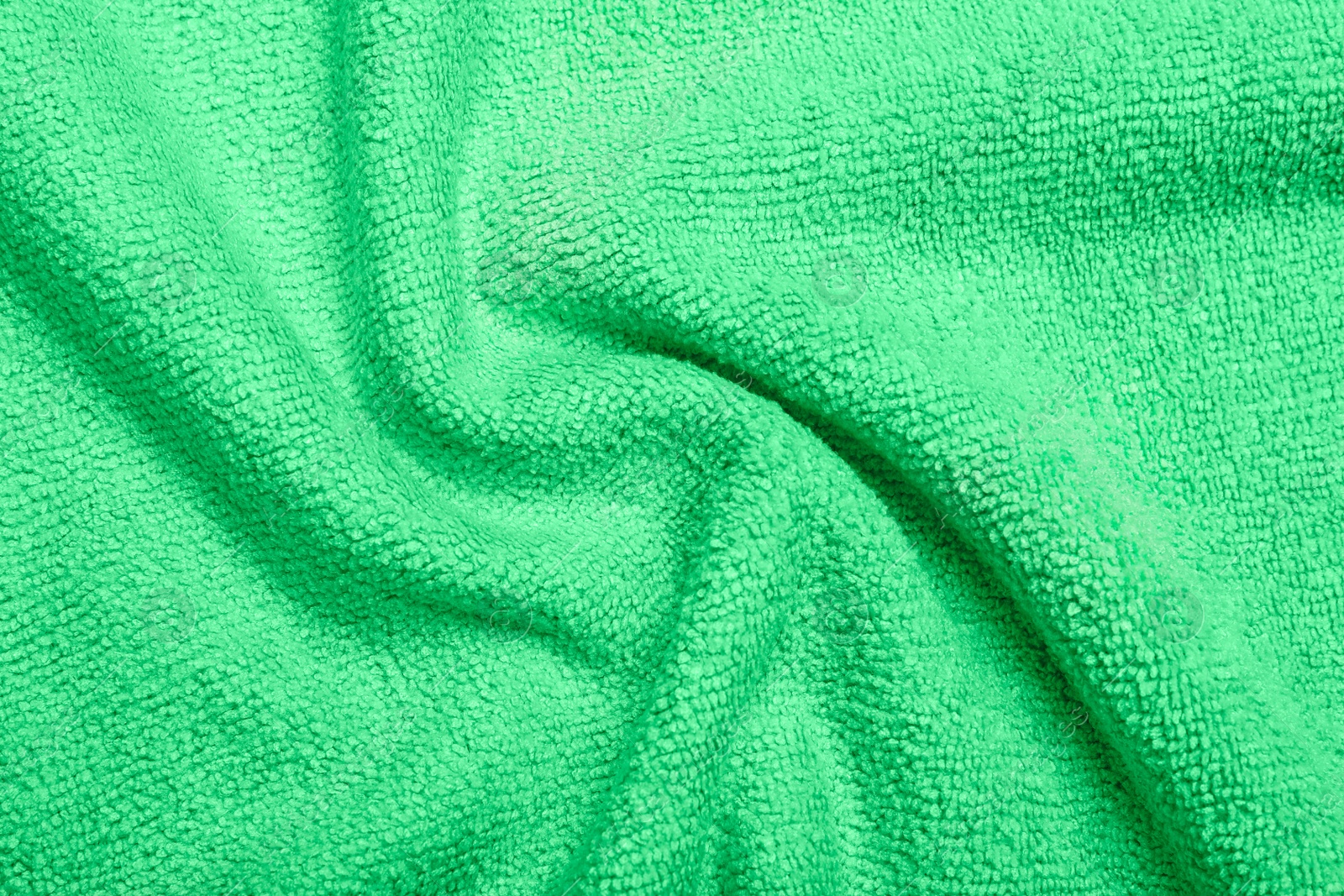 Photo of Crumpled light green microfiber cloth as background, closeup