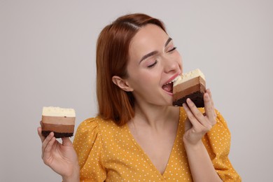 Photo of Young woman eating pieces of tasty cake on light grey background