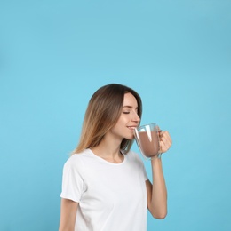 Photo of Young woman drinking chocolate milk on light blue background. Space for text