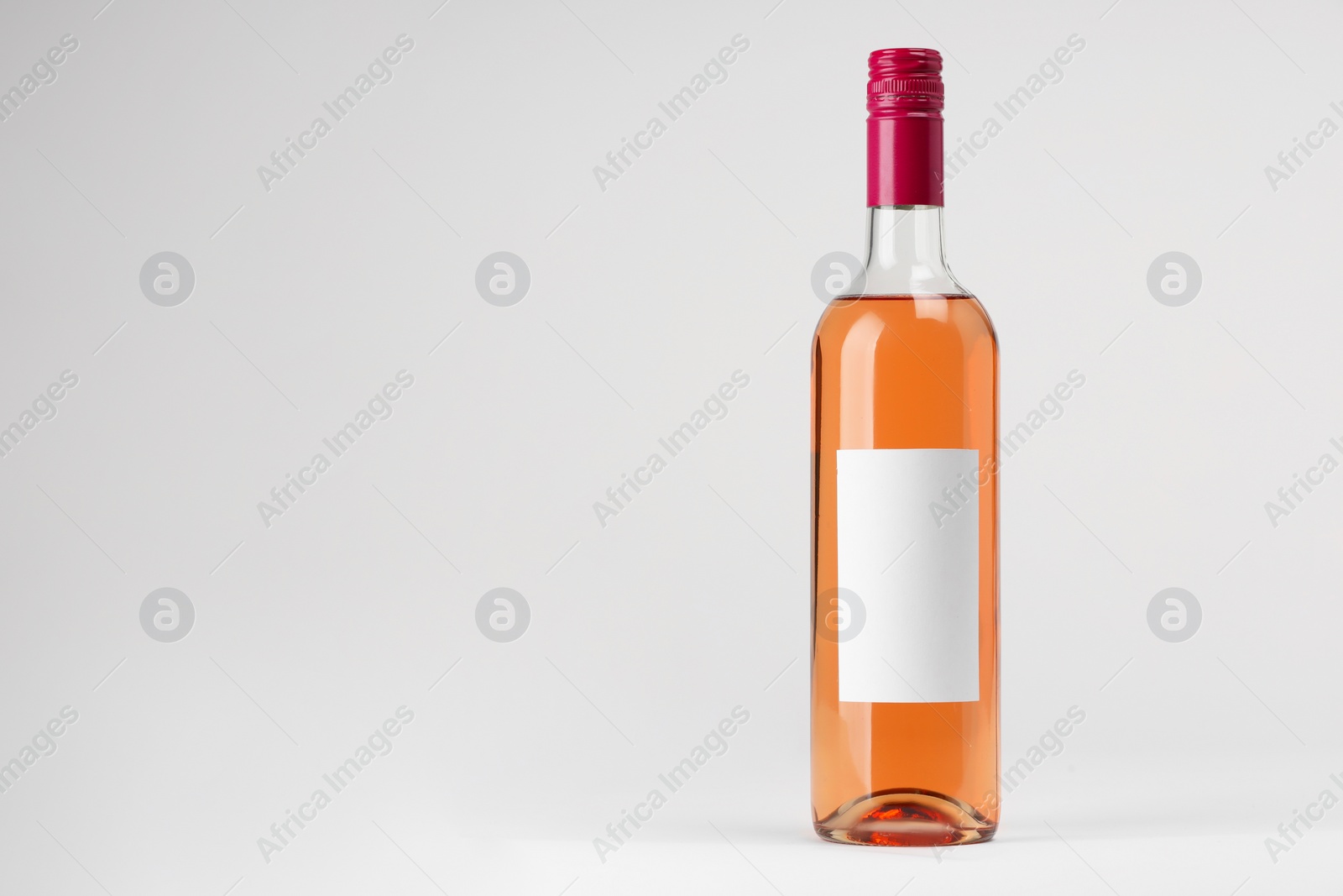 Photo of Bottle of tasty rose wine on white background, space for text