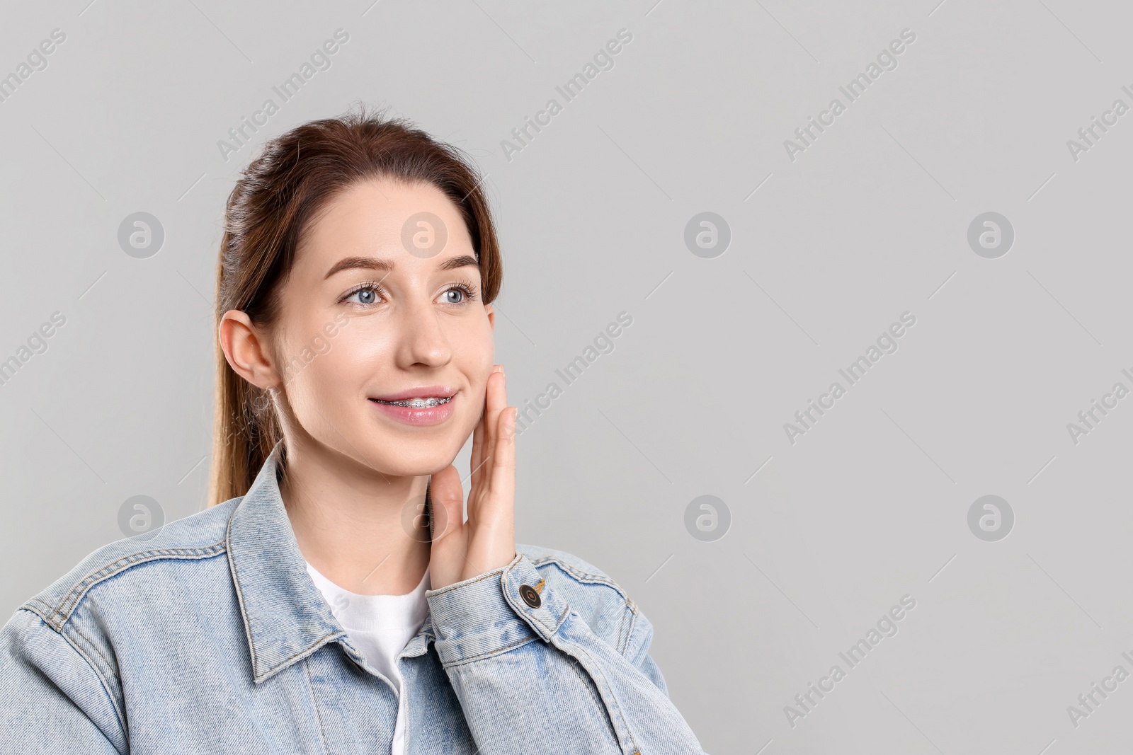 Photo of Portrait of smiling woman with dental braces on grey background. Space for text