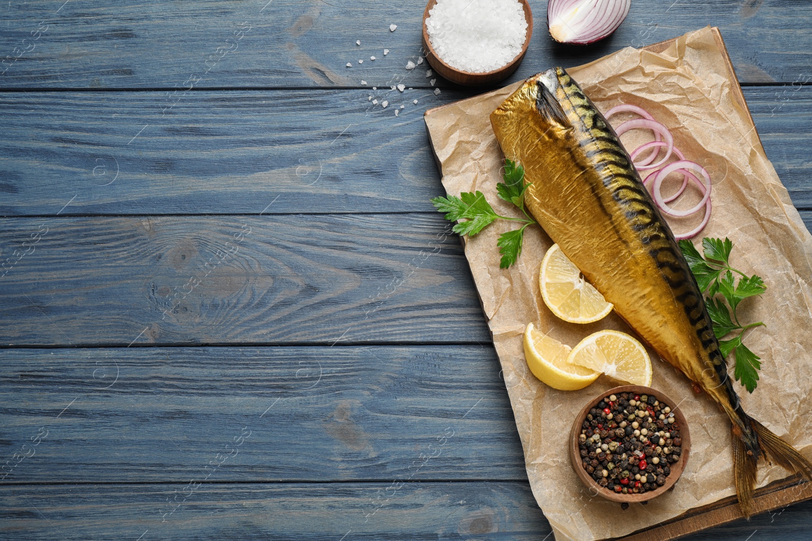 Photo of Tasty smoked fish on blue wooden table, flat lay. Space for text