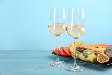 Photo of Delicious exotic fruits and wine on light blue wooden table. Space for text