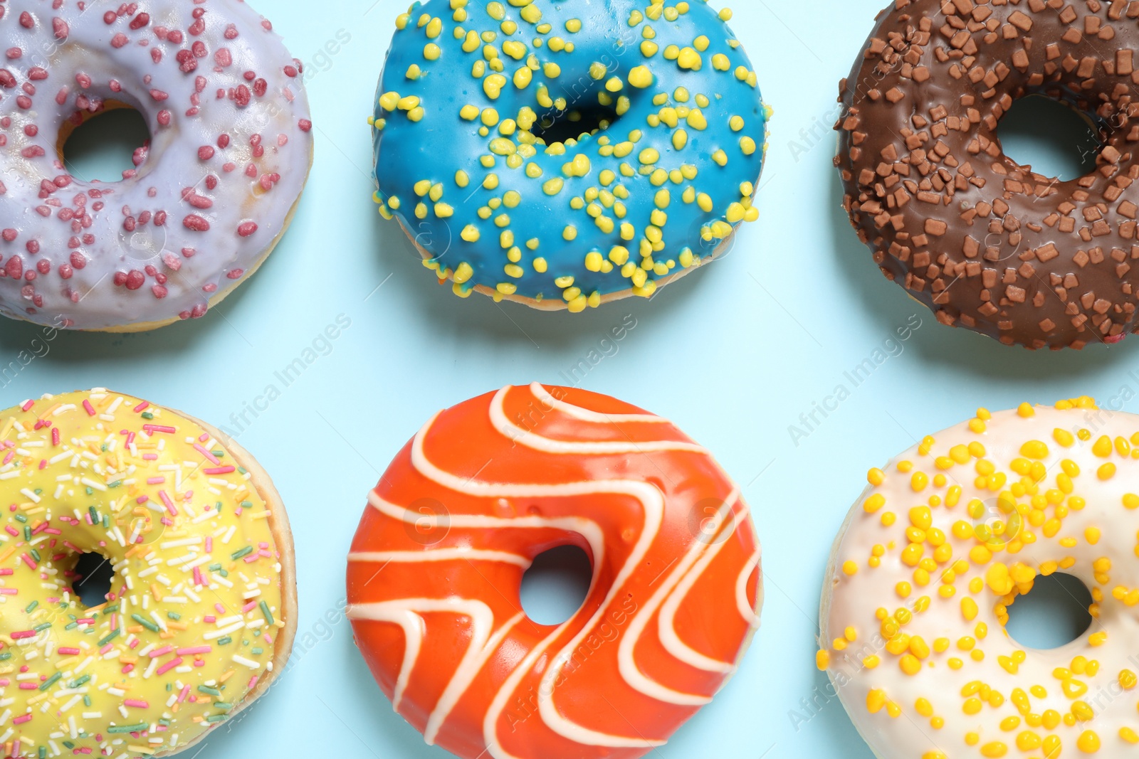 Photo of Delicious glazed donuts on light blue background, flat lay