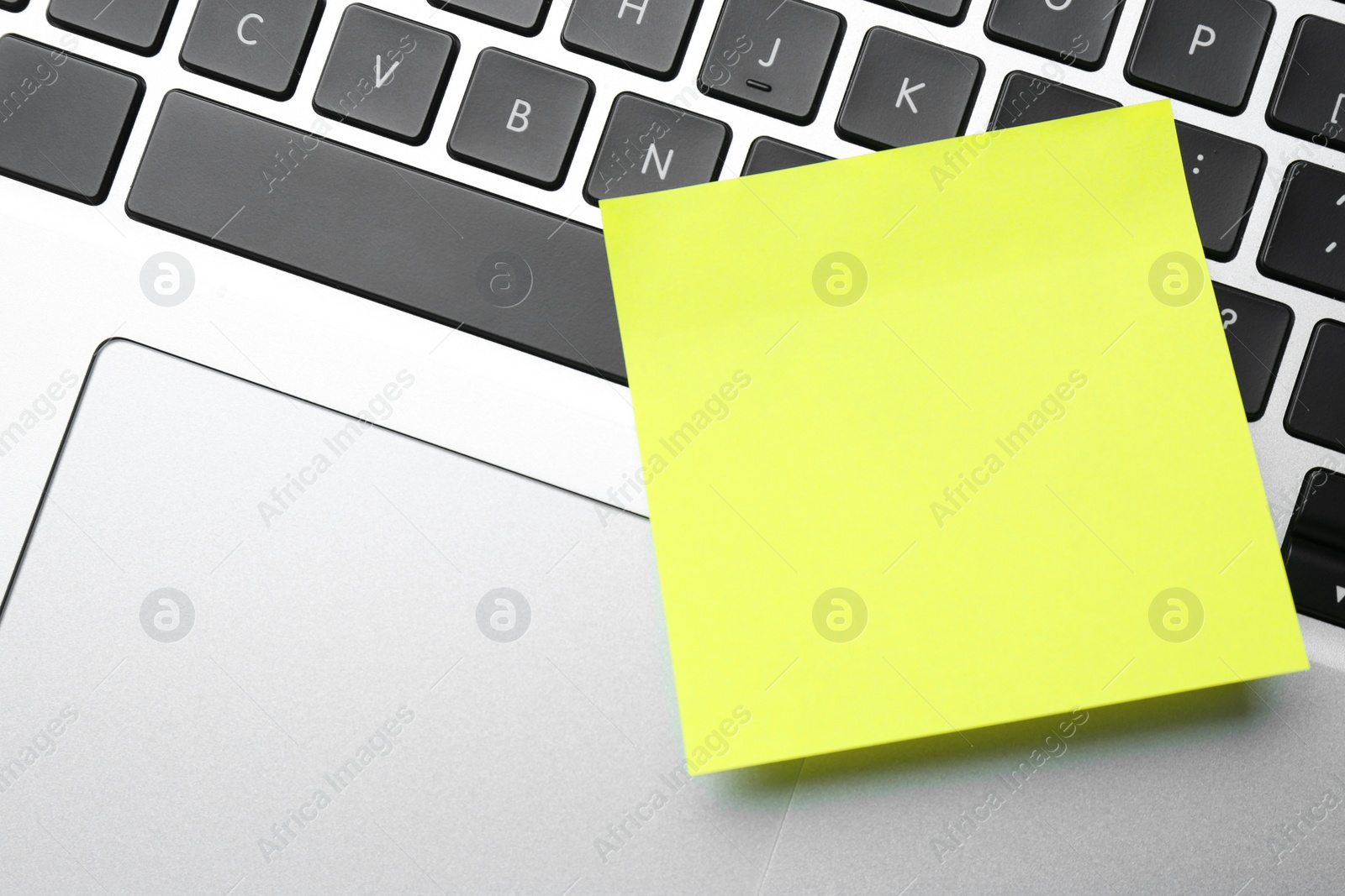 Photo of Empty sticky note on laptop, top view. Space for design
