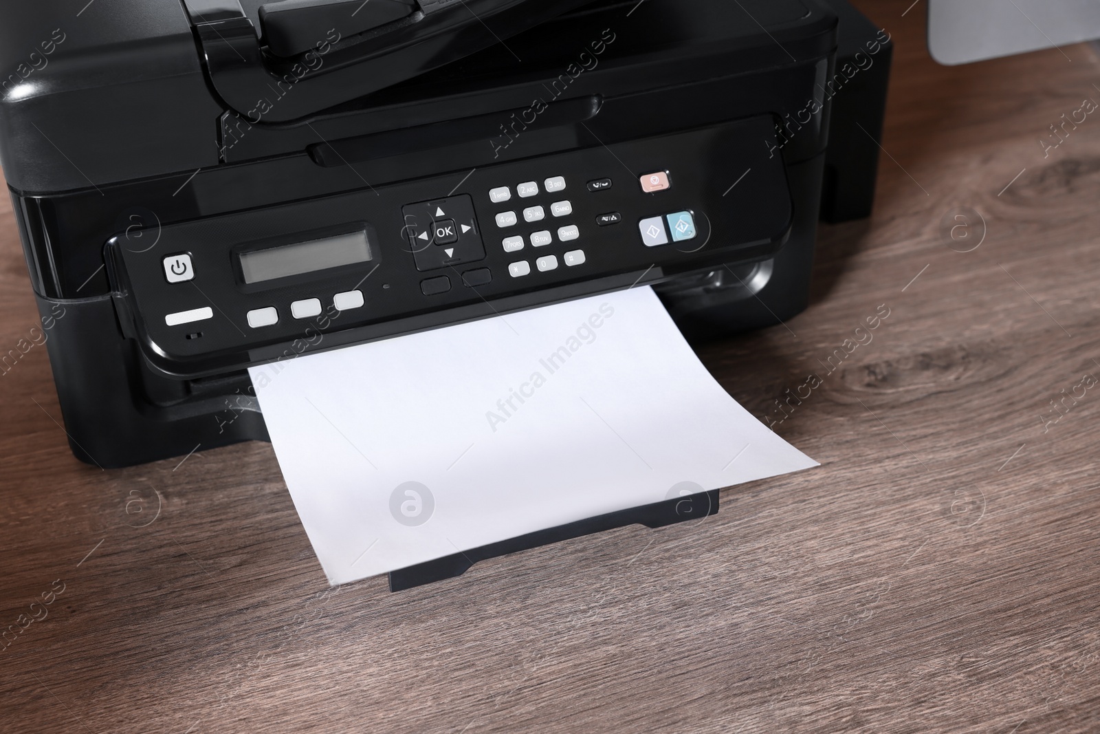 Photo of Modern printer with paper on wooden desk at home, closeup