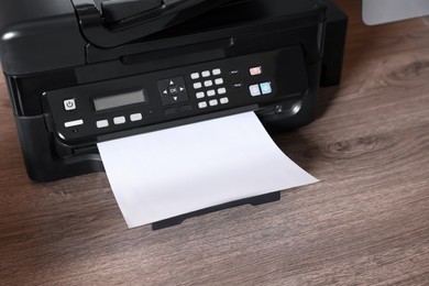 Photo of Modern printer with paper on wooden desk at home, closeup