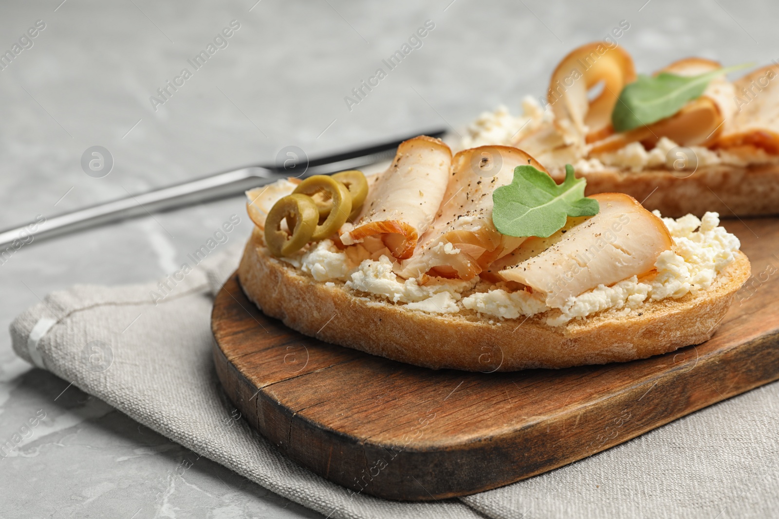 Photo of Board with delicious chicken bruschettas on grey marble table