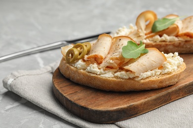 Photo of Board with delicious chicken bruschettas on grey marble table